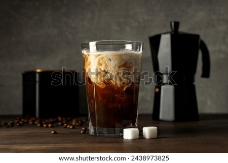 Glass with iced coffee drink, coffee maker, coffee bean and sugar on gray background Royalty-Free Stock Photo #2438973825