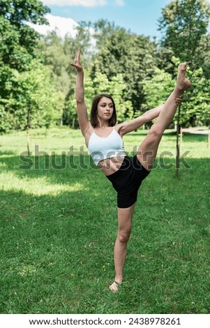 young slim fitness woman doing morning yoga pilates exercise in summer park. Healthy lifestyle, sport concept Royalty-Free Stock Photo #2438978261