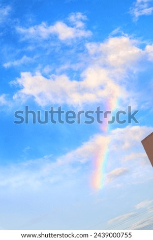 Rainbow appears during the day in the blue sky.