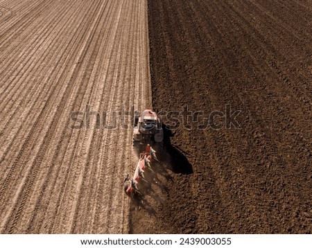 High-angle shot of a tractor with plow tilling the soil, preparing a field for planting