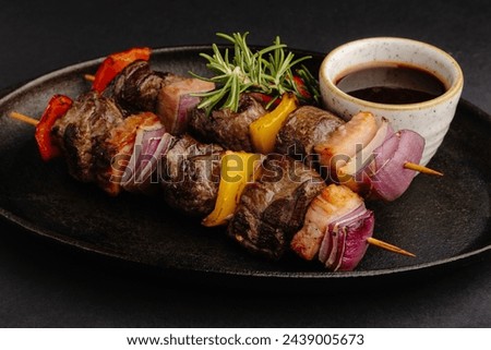 Tender beef, bell peppers, onions expertly grilled on skewers, served with a flavorful dipping sauce. A visually appealing dish with a perfect blend of flavors, sure to please at any event. Royalty-Free Stock Photo #2439005673