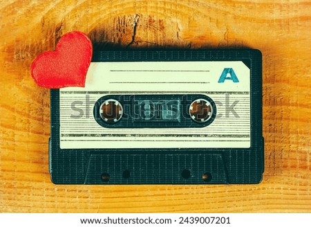 Old Audio Cassette with a Red Heart on the Wooden Planks Background closeup