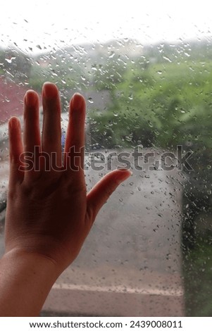 His hand was touching the window glass in the rain, looking like he was upset.