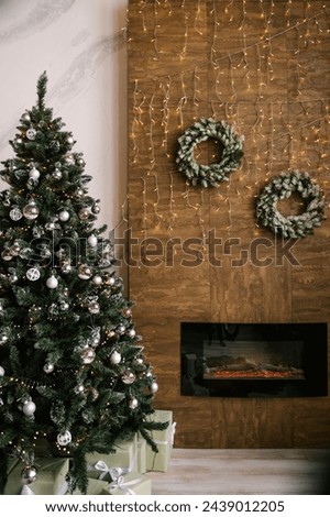 Fir wreaths with lights on the wall with a fireplace and a Christmas tree, New Year decor