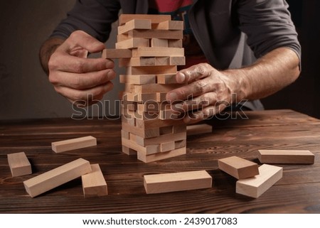 Hand of engineer playing a blocks wood tower game on blueprint or architectural project. Royalty-Free Stock Photo #2439017083
