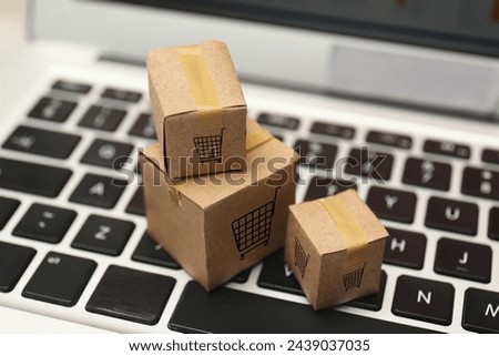 Internet store. Small cardboard boxes with shopping carts on laptop, closeup