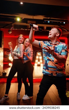 Joy and music. Happy young man  is singing in karaoke nightclub
