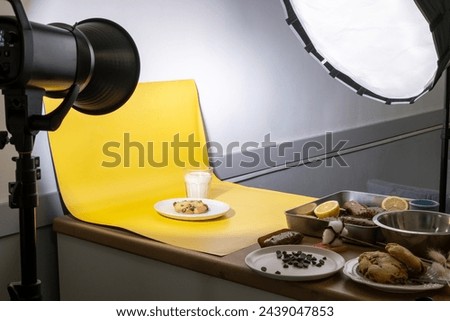Close-up of setup for taking photo of cookie with glass of milk on yellow background. Photo studio for food stock photographer. Backstage process with special light equipment. Artificial light source