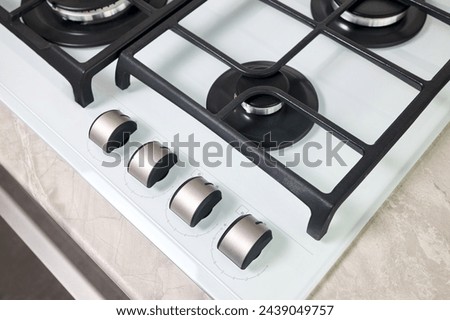 Hob cooker stove oven made of white glass grill stainless steel control knobs selective focus over out of focus oven with burner on countertop made of ceramic stoneware background.