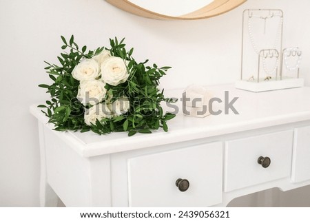Wedding bouquet, ring box and jewelry holder on wooden white dressing table
