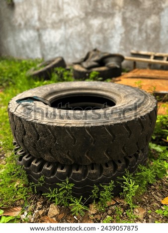 a pile of used truck tires overgrown with weeds
