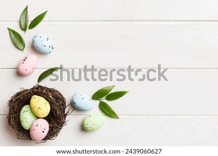 Colorful easter eggs in nest on table background with copy space top view.