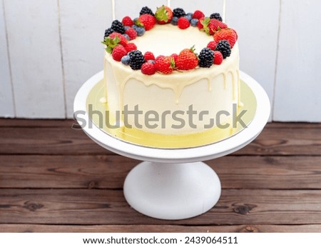 Cheesecake with fresh strawberry, raspberry, blueberry and blackberry, melted white chocolate on rustic wooden cakestand and background Royalty-Free Stock Photo #2439064511