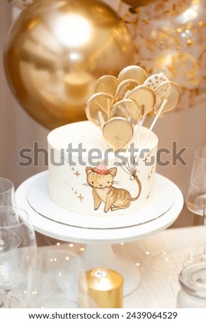 Decorated party table. Birthday cake with handpainted image of a little cat holding golden ballons