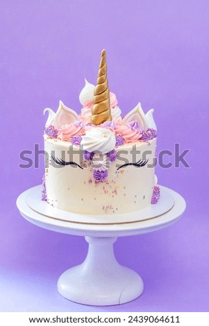 Colorful birthday cake with sprinkles, pink, blue and purple deocrations. Plain background, copy space