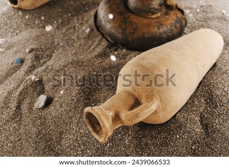 Antique clay amphorae in sandy landscape, hinting at archeological significance. Their weathered state longtime exposure. Part of larger historical site Royalty-Free Stock Photo #2439066533