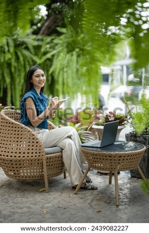 Young asian woman work relaxing in garden with laptop. Write notes in a notebook.