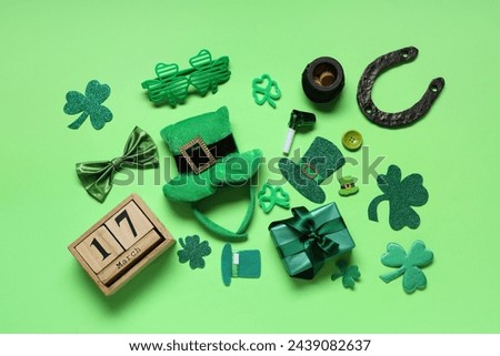 Leprechaun hat with calendar, gift box and decor for St. Patrick's Day on green background