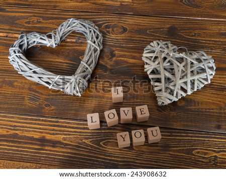 Closeup of letters which built the word I LOVE YOU with two heart shapes and a wooden background