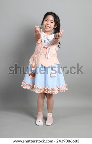 The little cut Asian girl with fancy dressed standing on the grey background.
