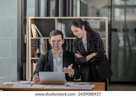 Company CEO and Top Manager Talking, Using Laptop Computer in office. Two Successful Professional People Brainstorm, Find Solution to Their e-Commerce Software Investment Strategy