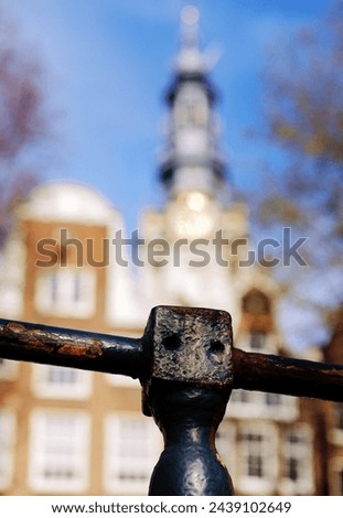 Close up of a bridge railing at the Raamgracht canal in Amsterdam picturing in soft blurred focus canal houses and the church tower of the Zuiderkerk