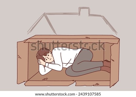 Homeless man sleeps in box on street after being fired from job due to labor market crisis. Homeless guy needs help from charity or shelter to solve temporary difficulties that cause poverty Royalty-Free Stock Photo #2439107585