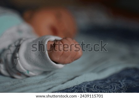 Close-up of a newborn's small fist, softly curled, with a gently blurred background, reflecting the delicate strength and purity of infancy.  Royalty-Free Stock Photo #2439115701
