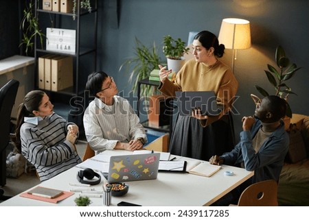 Middle Eastern woman presenting ideas to multiethnic business team during meeting in office