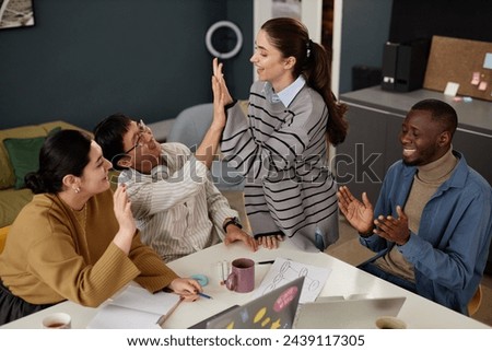 Multiethnic group of people high five during successful business meeting in office and celebrating