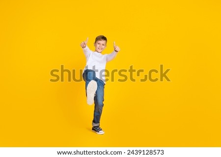 Full length photo of funky confident kid dressed white shirt showing two thumbs up empty space isolated yellow color background