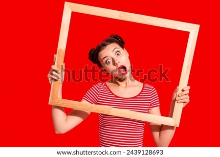 Portrait of her she nice crazy cute charming attractive glamorous winsome playful girl in striped t-shirt holding in hands wooden frame film actress movie isolated on pink background
