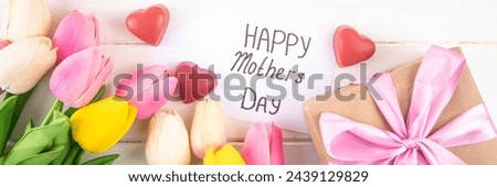 Mother day background with tulip flowers bouquet, gift box with pink ribbon and Happy Mother Day tag. Greeting card background, flat lay for poster, brochures, booklets, promotional materials, website