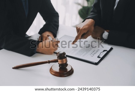 Justice and Law concept. Legal counsel presents to the client a signed contract with gavel and legal law or legal having team meeting at law firm in background