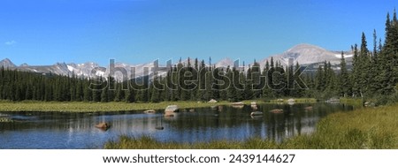 Brainard Lake in Colorado's Indian Peaks Wilderness.  Blue sky, grassy shores and pine trees along shore in Colorado high country.   Royalty-Free Stock Photo #2439144627