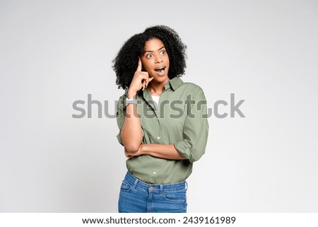 In a moment of sudden realization, an African-American woman gestures towards her head, her expression one of surprised insight, on a simple background Royalty-Free Stock Photo #2439161989