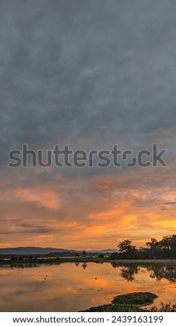Orange colored Cirrus clouds at sunset over calm lake water
