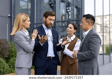 Sympathetic coworkers gathering around sad caucasian man with spread arms and looking at colleague with sorrow. Pity manager telling about unsuccessful results and being scared about getting fired. Royalty-Free Stock Photo #2439171357