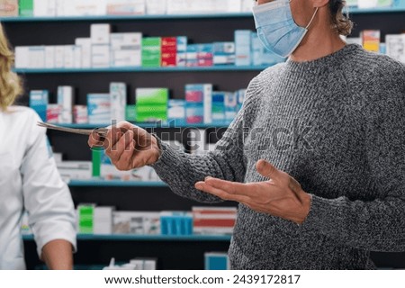 Man in medical mask paying for pills by cash money at pharmacy counter. Dollar payment: Man completes transaction with cash at pharmacy.