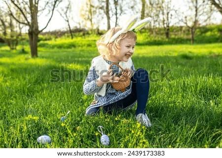 Excited child joins the Easter hunt, gleefully gathering eggs in their basket, creating memories of laughter and fun. Royalty-Free Stock Photo #2439173383