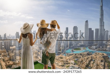 A elegant family on a city break vacation enjoys the panoramic view over the skyline of Dubai, UAE Royalty-Free Stock Photo #2439177265