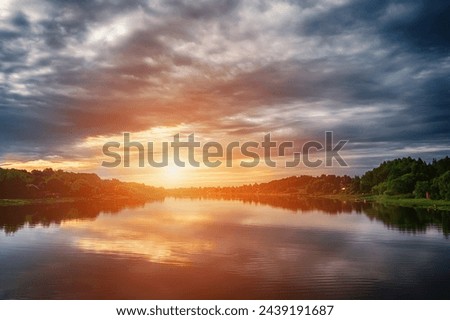 Dramatic sunset in the landscape of the banks of the Volkhov River. In the distance is a cruise ship and a medieval fortress. Royalty-Free Stock Photo #2439191687