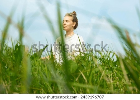 A young woman sits in the grass. Lifestyle concept