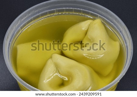 A simple wonton soup in a plastic container.