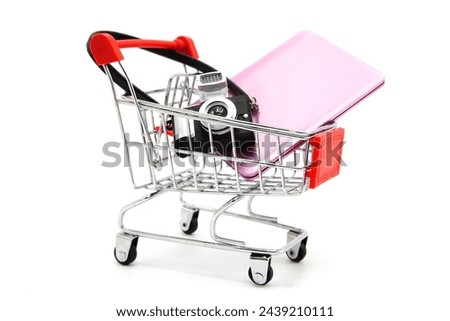 Shopping supermarket cart with camera and laptop inside isolated on a white background. Online shopping. Buying electronic equipment.