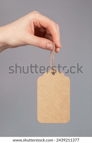 Hand holding paper price tag, gift label on cord, twine isolated on white background.