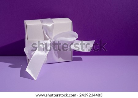 White gift box on a purple background. Holiday card