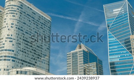 Modern skyscrapers with many windows timelapse in famous financial and business district of Paris - La Defense. Reflections on a glass with blue clouds and blue sky at summer day