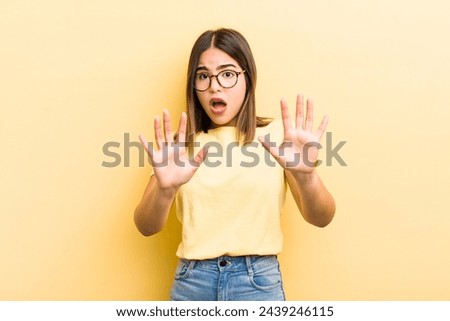 pretty hispanic woman feeling stupefied and scared, fearing something frightening, with hands open up front saying stay away