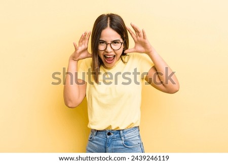 pretty hispanic woman screaming in panic or anger, shocked, terrified or furious, with hands next to head